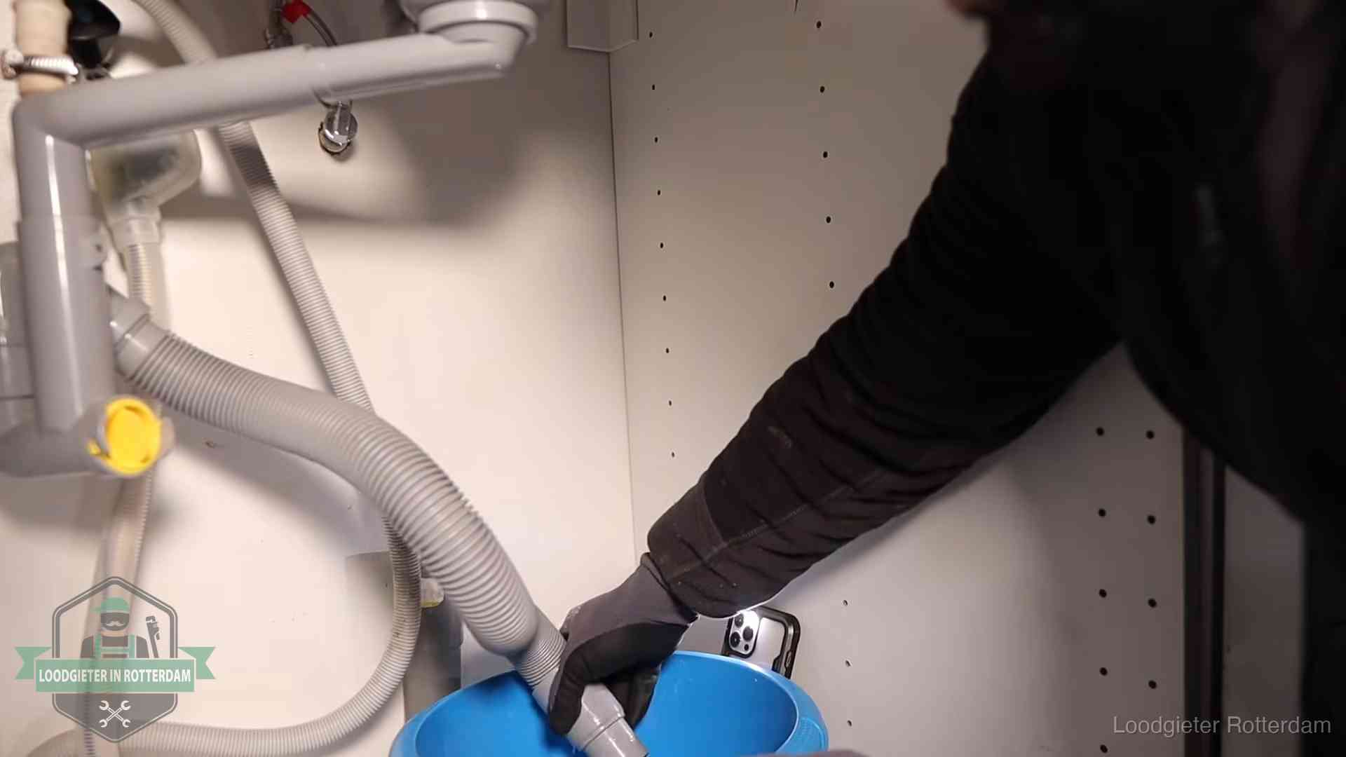 Afvoerslang loopt leeg in een emmer onder de gootsteen in Rotterdam, een klus die je zelf kunt doen