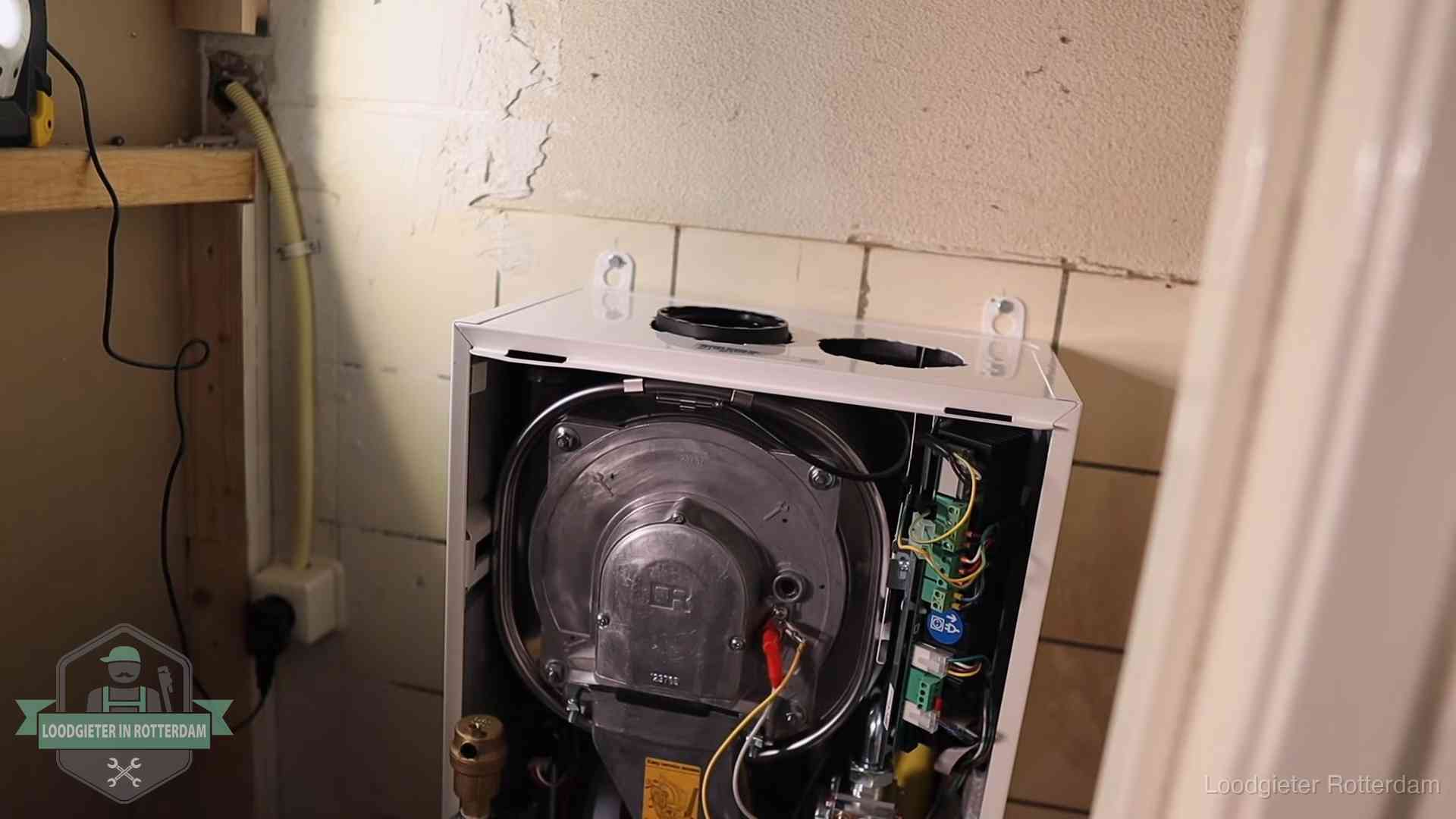 Geopende cv-ketel tijdens een onderhoudsbeurt in Rotterdam, met brander en warmtewisselaar zichtbaar