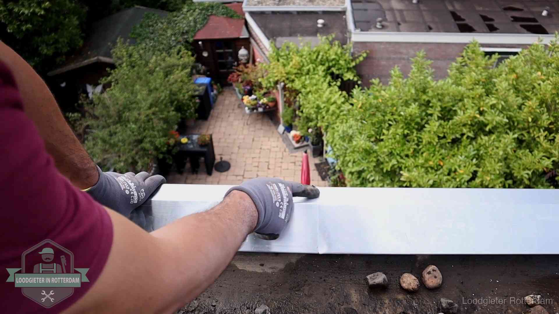Daklekkage geregeld in Rotterdam Vakman plaatst een daktrim op de dakrand van een woning in Rotterdam