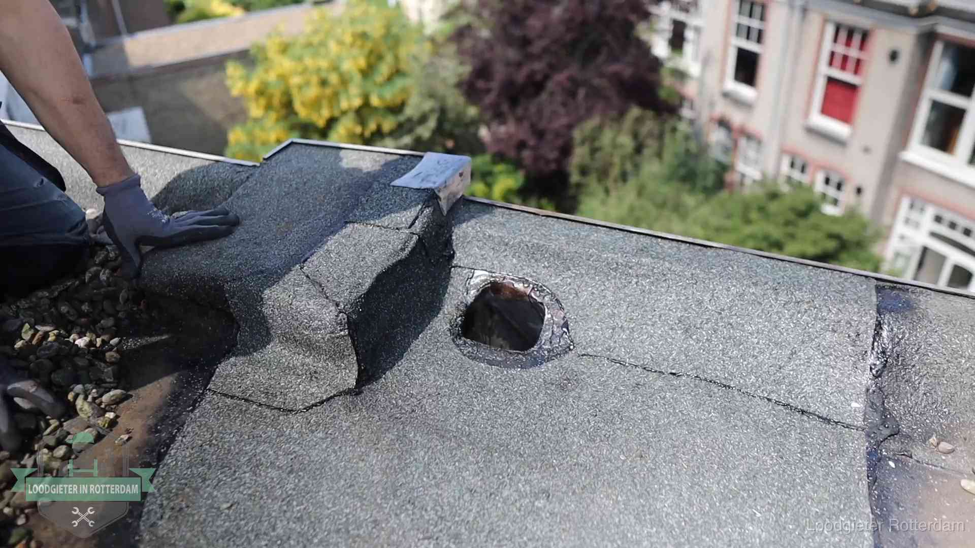 Daklekkage-inspectie op een plat dak in Rotterdam Loodgieter inspecteert een beschadigd bitumen plat dak tijdens een daklekkage-inspectie in Rotterdam