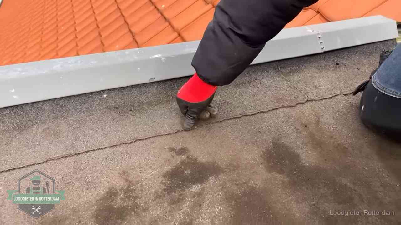Lekkage bij de naad van een plat dak in Rotterdam Vakman wijst een naad met vochtplekken aan op een bitumen plat dak in Rotterdam
