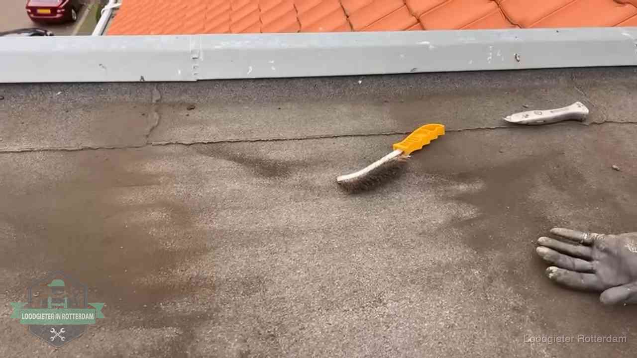 Kosten van daklekkage-reparatie in Rotterdam Dakdekker bereidt een bitumen plat dak voor op reparatie bij de daktrim in Rotterdam