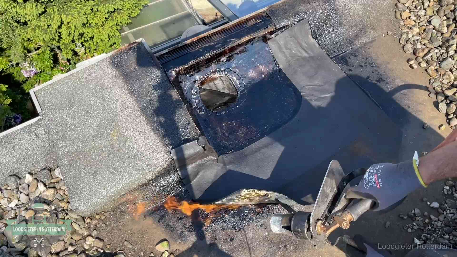 Daklekkage repareren in Rotterdam Dakdekker brandt bitumen rond een doorvoer tijdens een daklekkage-reparatie in Rotterdam