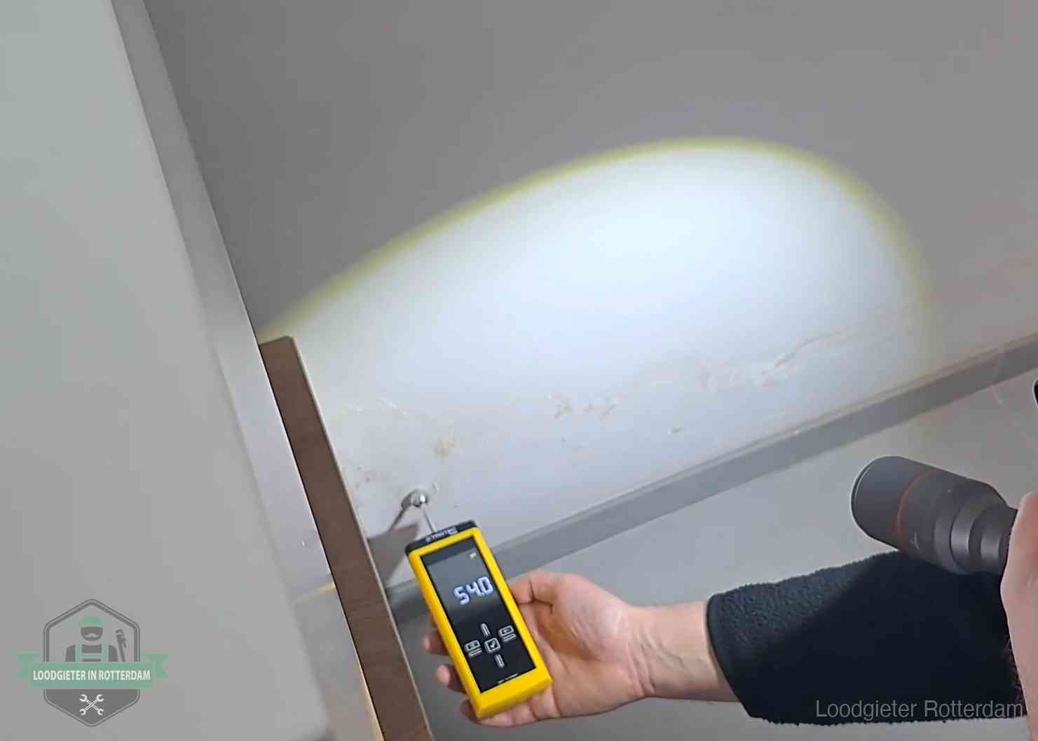 Vochtmeter tegen een natte wand met lekkagesporen in Rotterdam