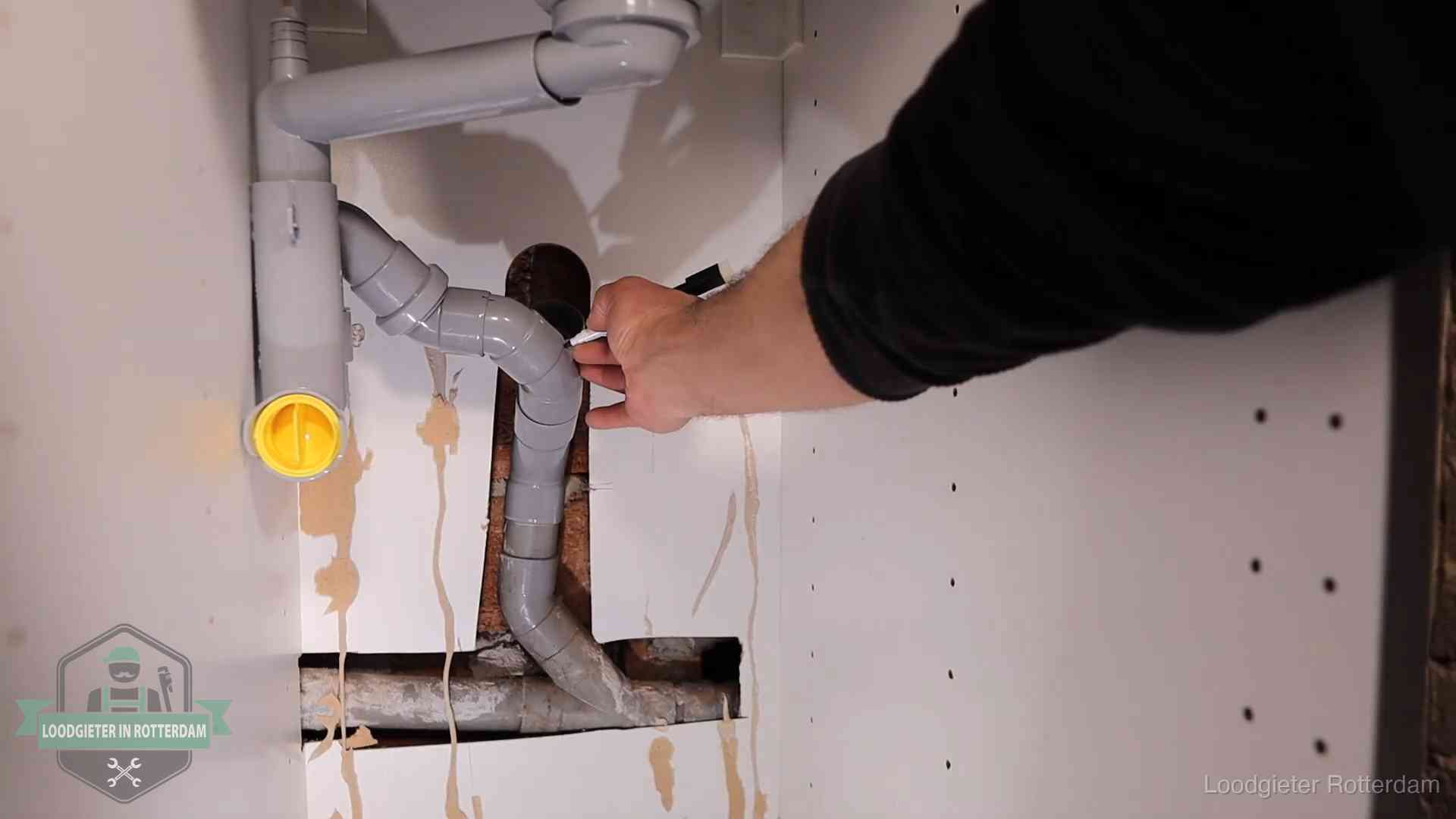 Loodgieter voor verhuurders en bedrijven in Rotterdam Loodgieter markeert een pvc-afvoerbuis onder een gootsteen in Rotterdam