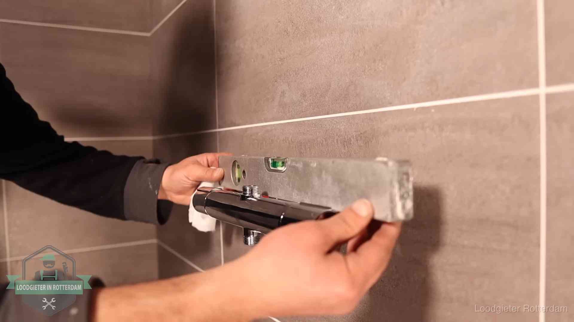 Loodgietersbedrijf voor sanitair in Rotterdam Loodgieter lijnt een douchekraan uit met een waterpas in een woning in Rotterdam