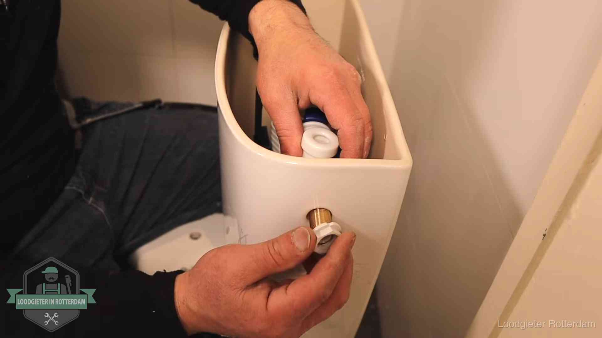 Loodgieter monteert de vlotterkraan van een stortbak bij een toilet in Rotterdam