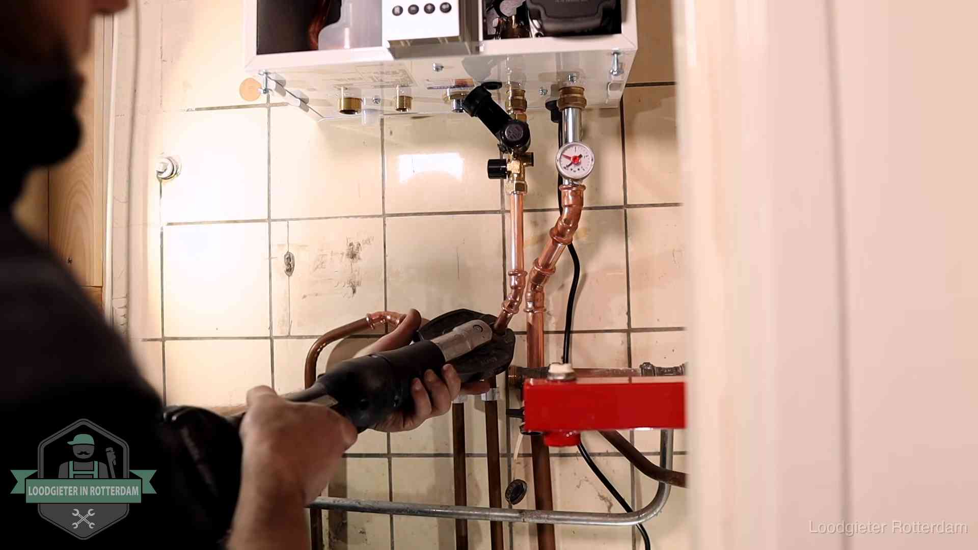 Monteur werkt aan de leidingen onder een cv-ketel in Rotterdam