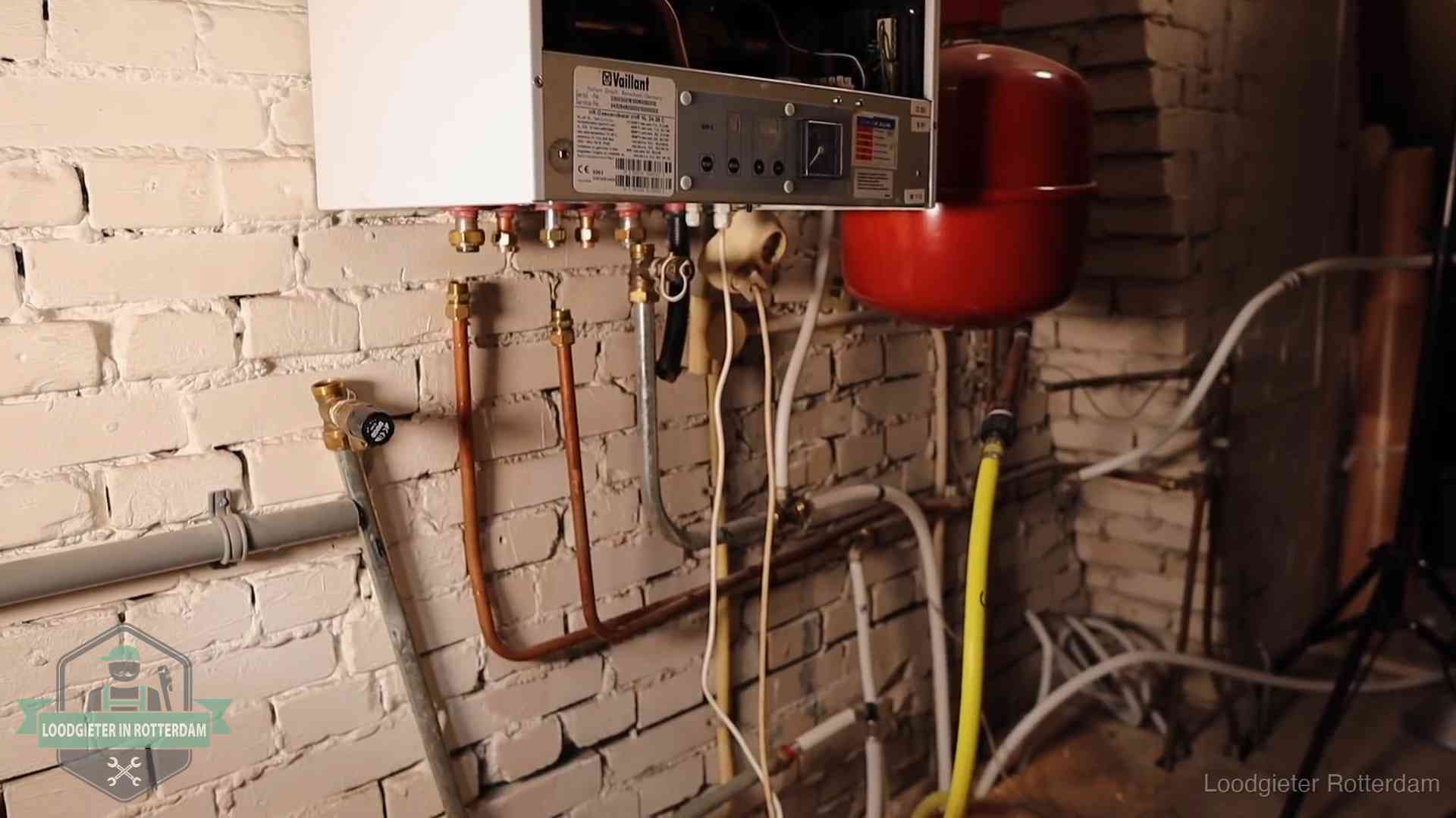 Verouderde cv-ketel met een wirwar van oude leidingen in een woning in Rotterdam