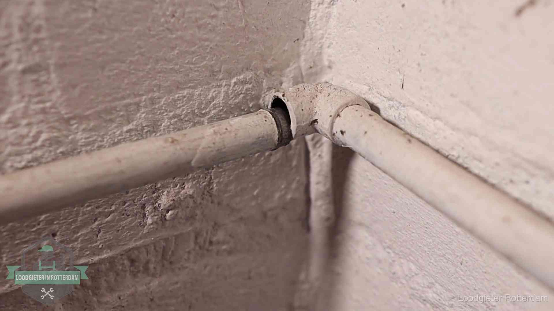 Oude geverfde waterleiding met een losliggende fitting in een woning in Rotterdam
