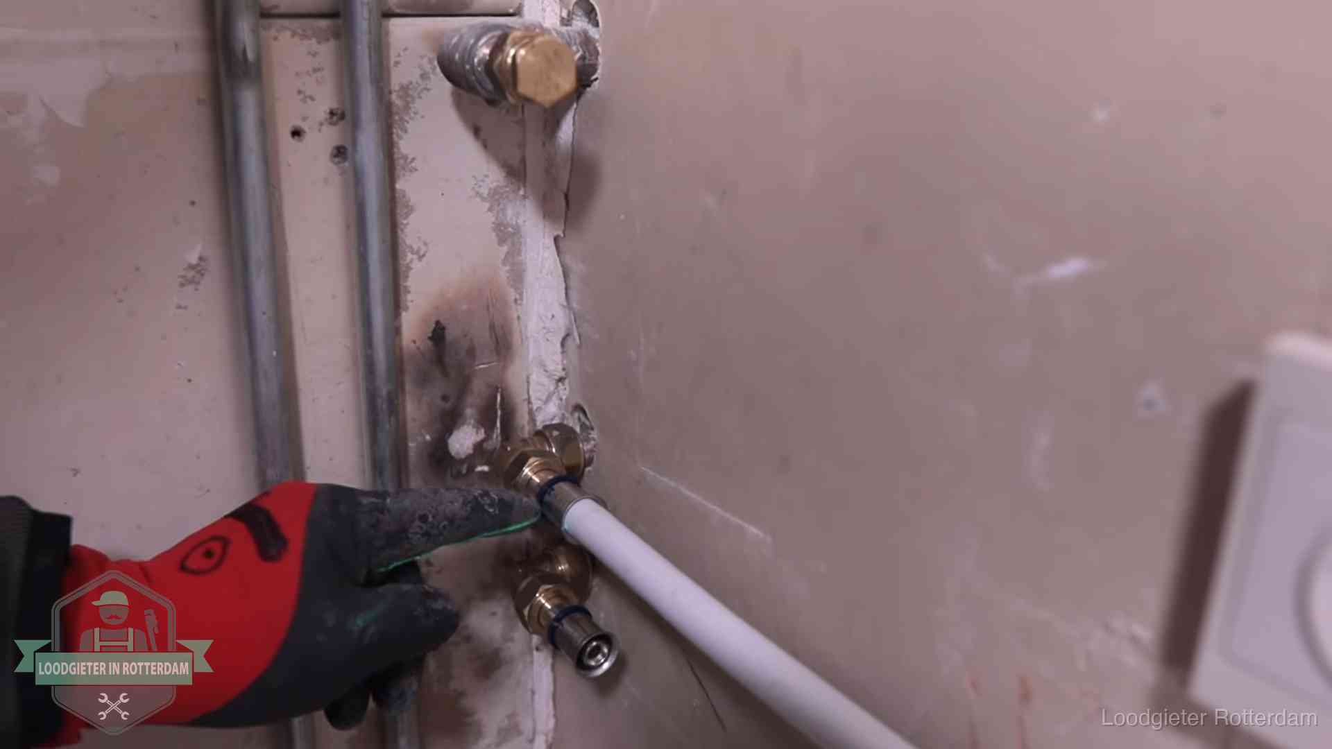 Garantie op loodgieterswerk in Rotterdam Loodgieter wijst de persfitting op nieuwe muuraansluitingen aan in een woning in Rotterdam