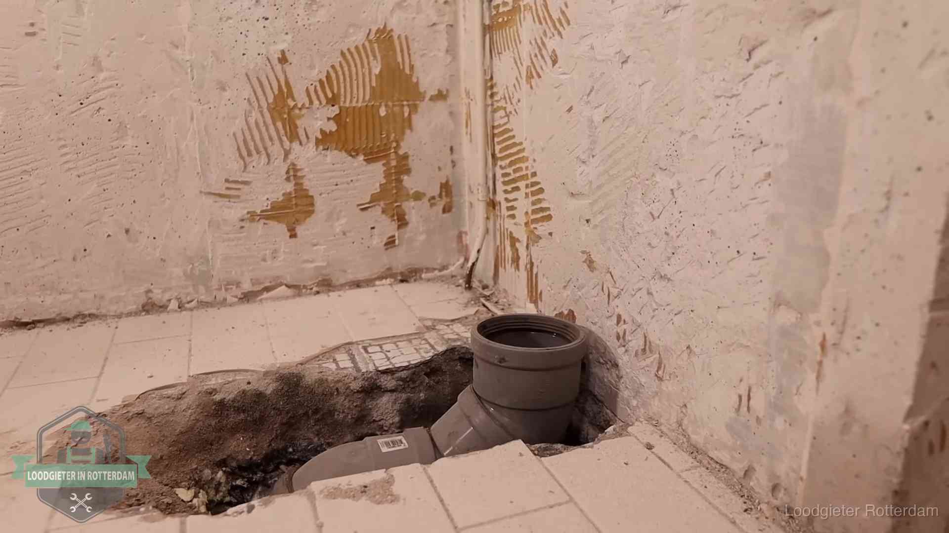 Opengebroken vloer met een nieuwe pvc-rioolbocht in een gegraven sleuf in Rotterdam