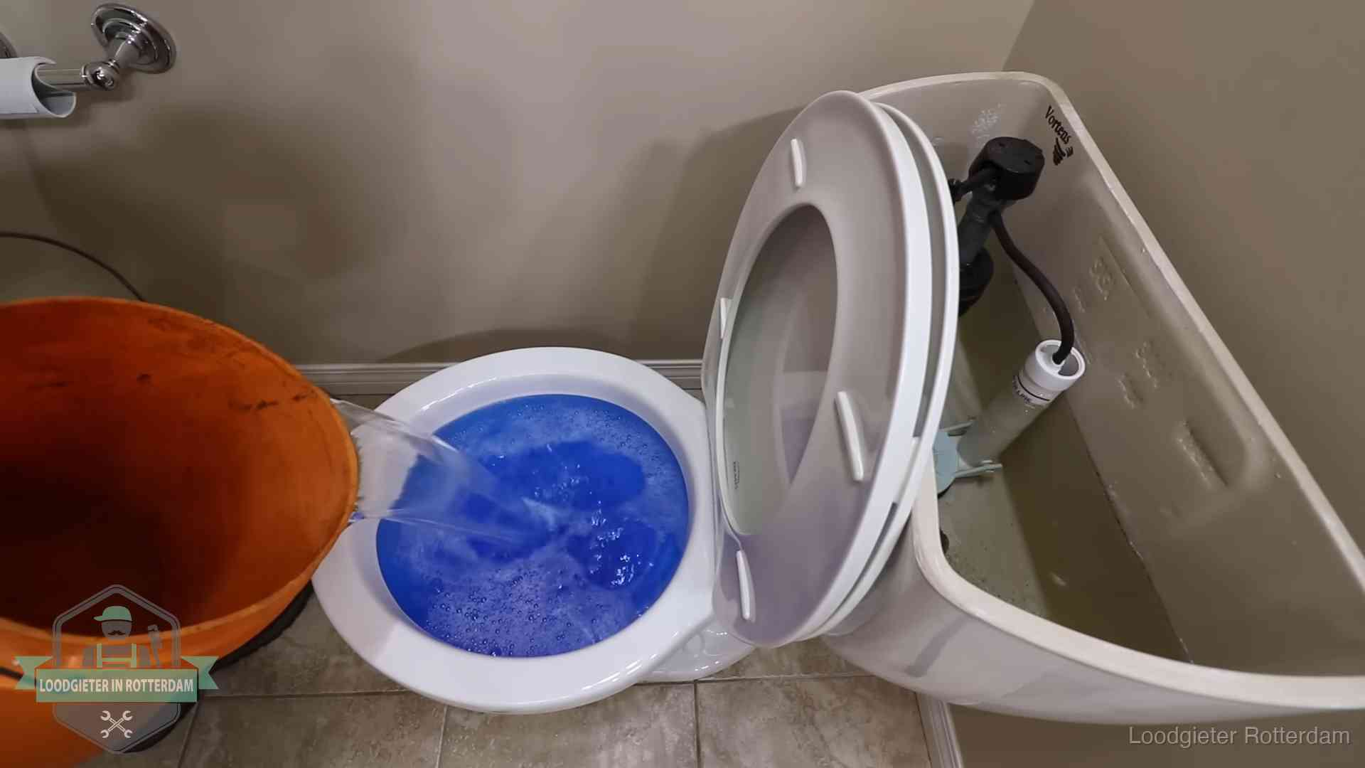 Water bij de wc-pot wordt met een emmer weggewerkt om schade te beperken in Rotterdam